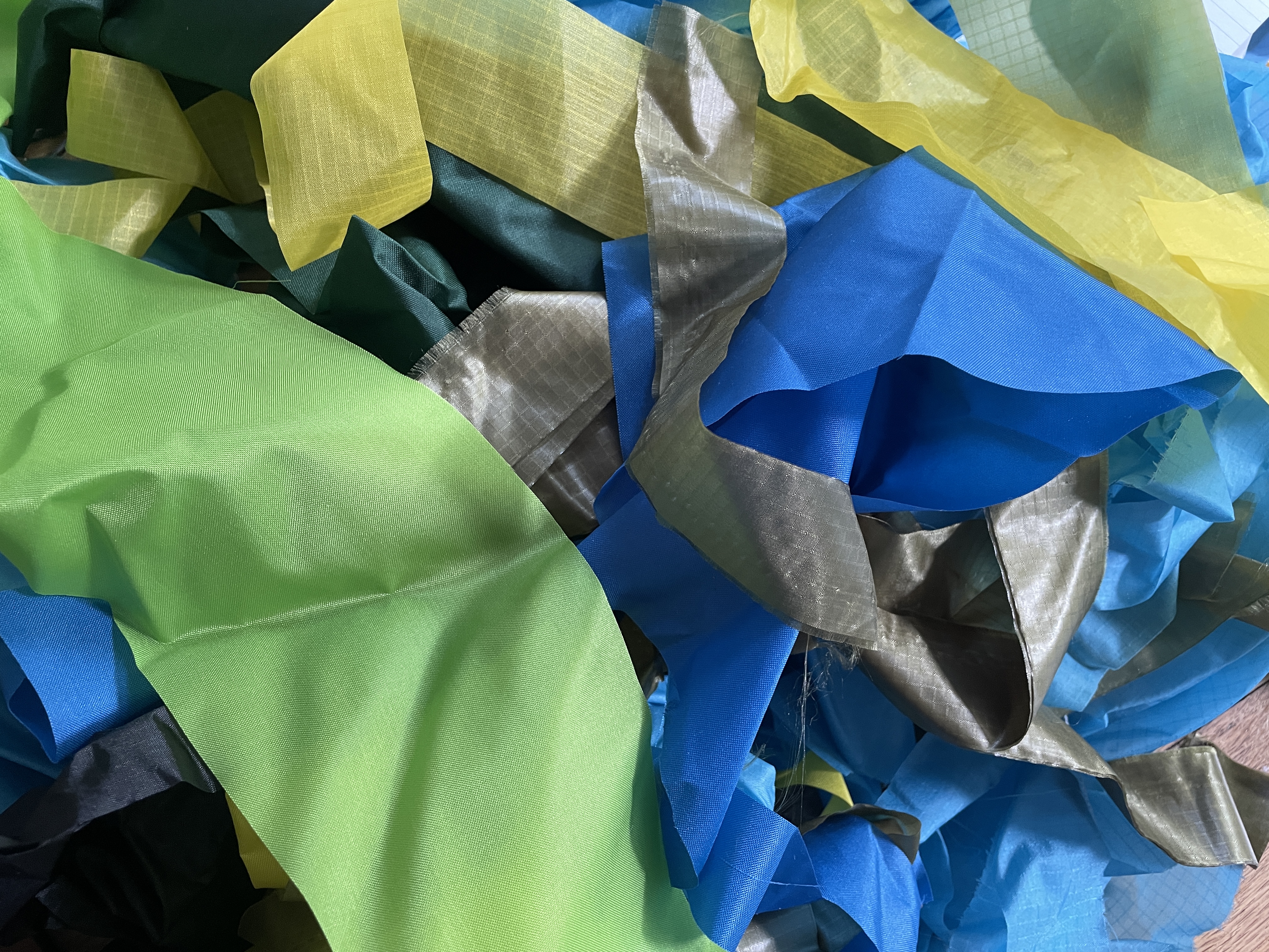 a jumbled pile of different coloured ripstop fragments, mostly greens, yellows and blues
