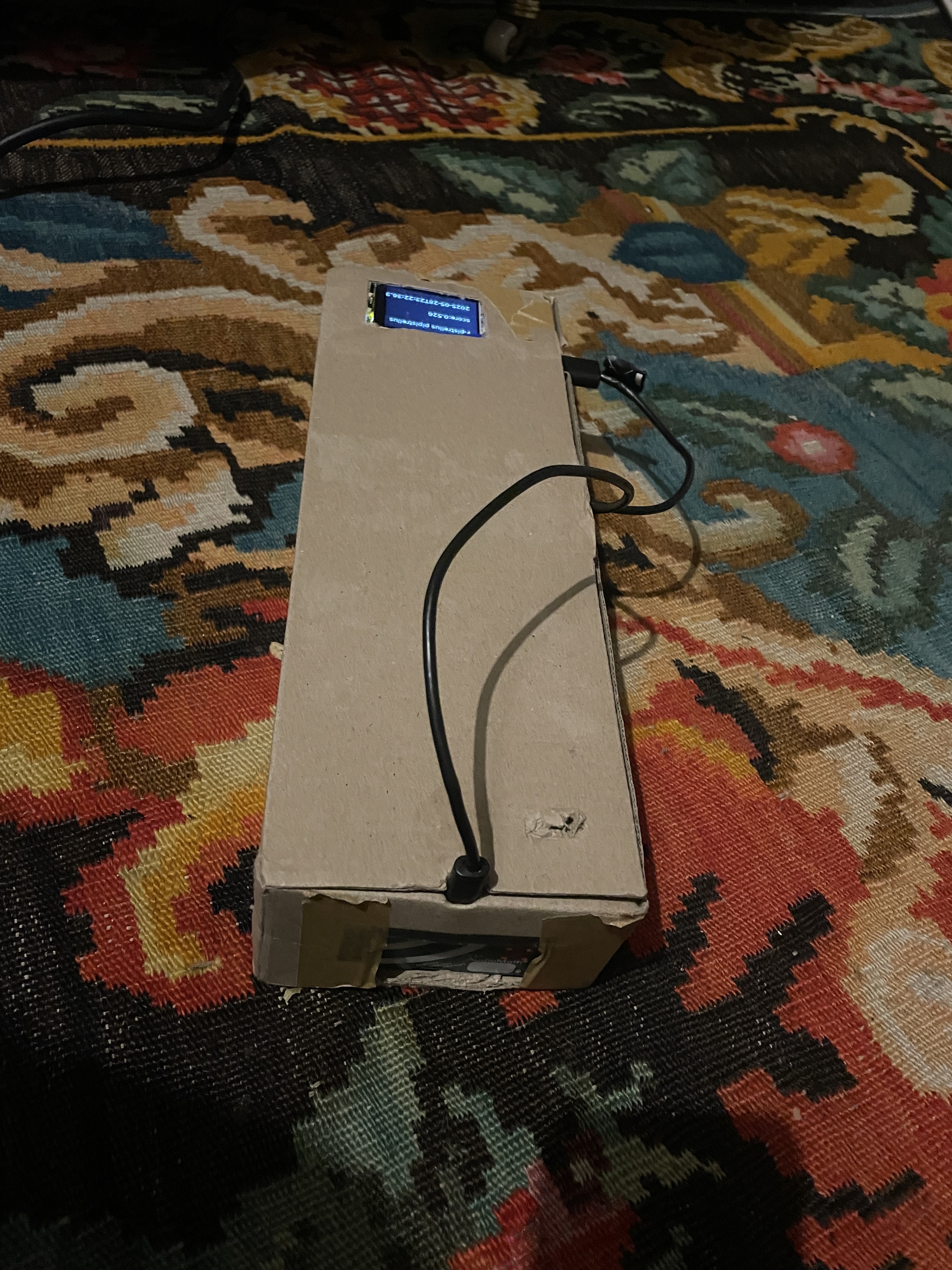 a cardboard box with an audiomoth mic at one end and a pi and screen at the other