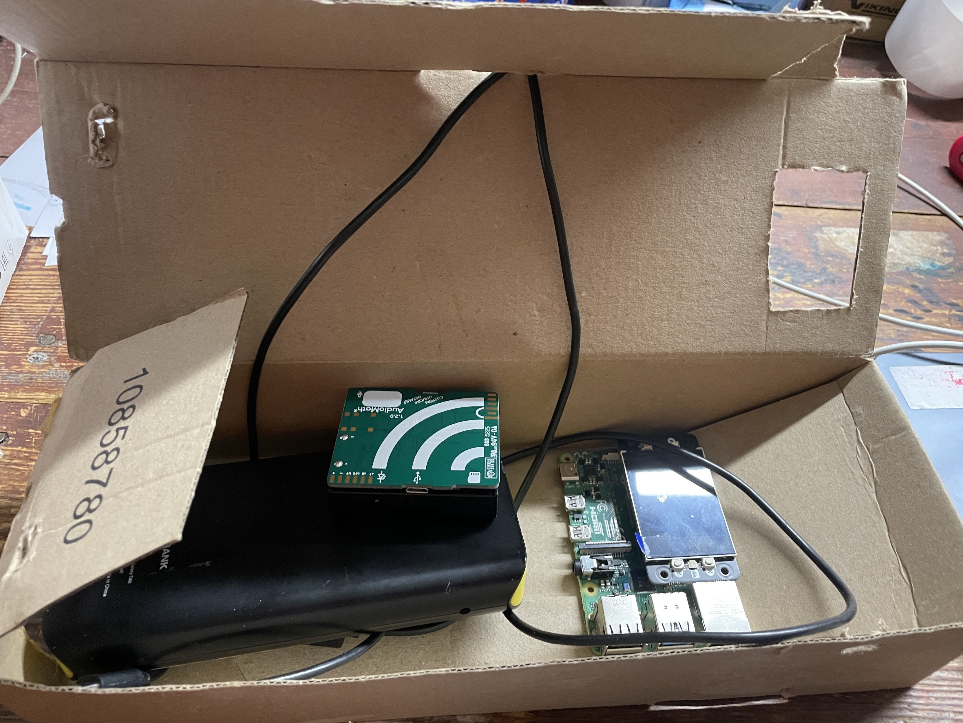 A cardboard box with a pi, mic, battery in it